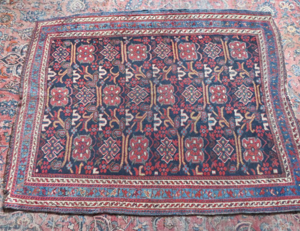 A rectangular hand-knotted antique Afshar rug featuring geometric floral motifs in terracotta red and sky blue on a deep navy blue background. View XVI
