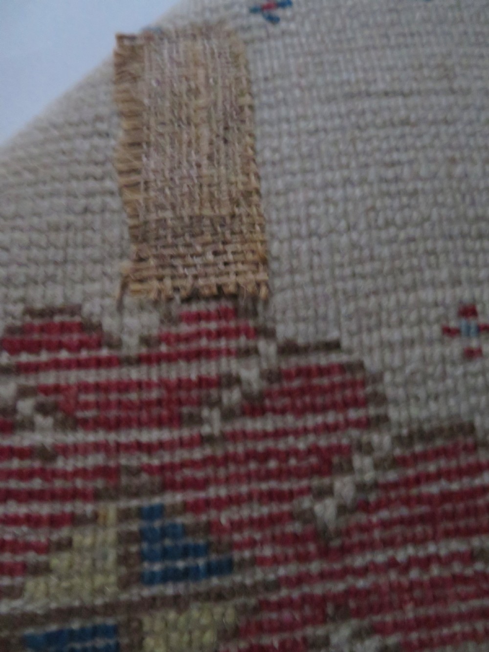 An antique Anatolian Konya wool rug featuring geometric red and blue symbols on a cream field with a sawtooth border. View XIII
