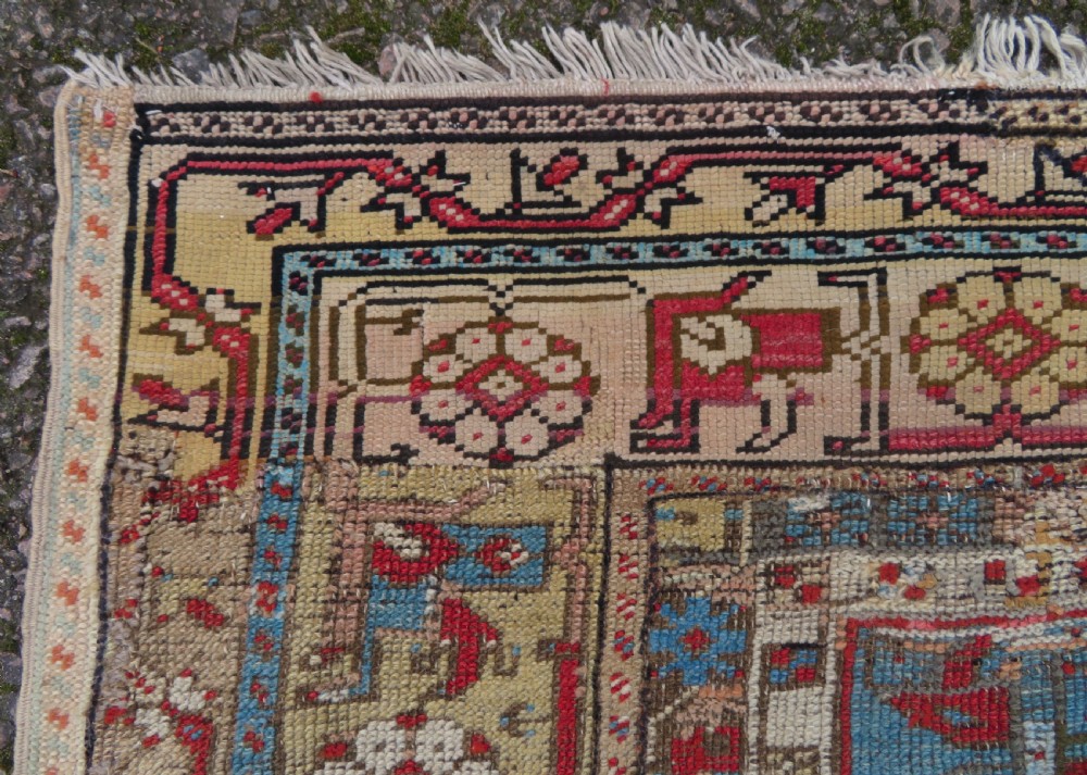 An antique hand-knotted Turkish Ladik wool prayer rug featuring a central pale blue mihrab niche, inverted tulip motifs, and multi-coloured geometric borders. View V