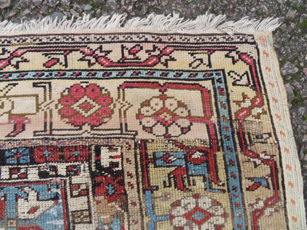 An antique hand-knotted Turkish Ladik wool prayer rug featuring a central pale blue mihrab niche, inverted tulip motifs, and multi-coloured geometric borders. View VII