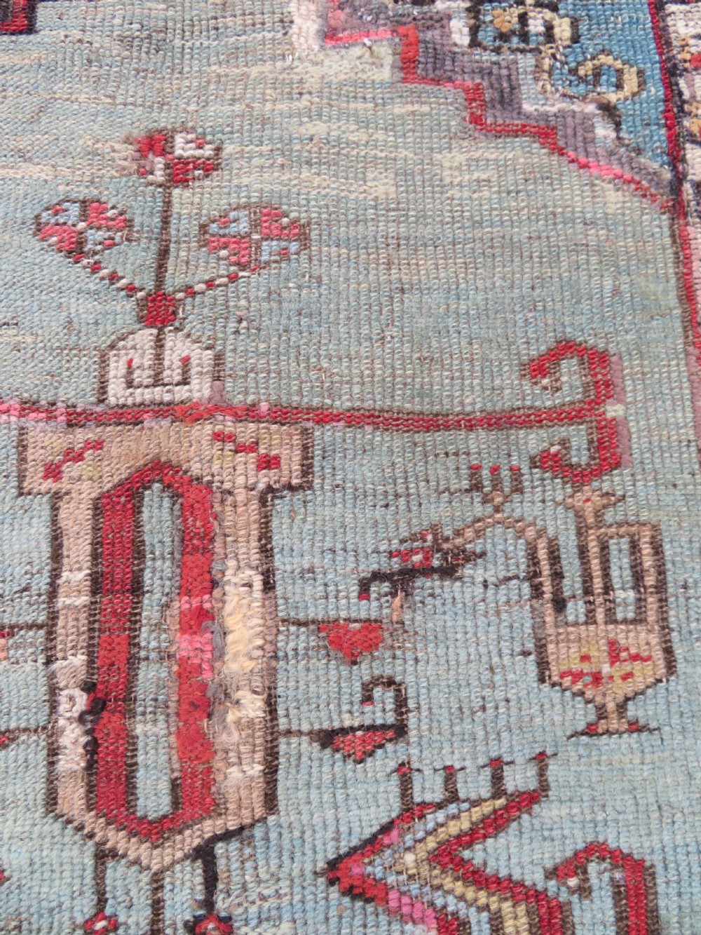 An antique hand-knotted Turkish Ladik wool prayer rug featuring a central pale blue mihrab niche, inverted tulip motifs, and multi-coloured geometric borders. View XI