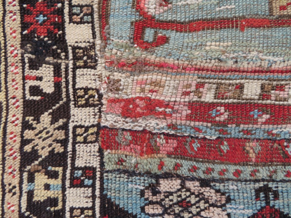 An antique hand-knotted Turkish Ladik wool prayer rug featuring a central pale blue mihrab niche, inverted tulip motifs, and multi-coloured geometric borders. View XVI
