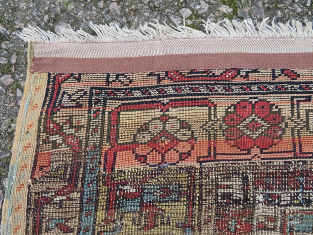 An antique hand-knotted Turkish Ladik wool prayer rug featuring a central pale blue mihrab niche, inverted tulip motifs, and multi-coloured geometric borders. View XIX