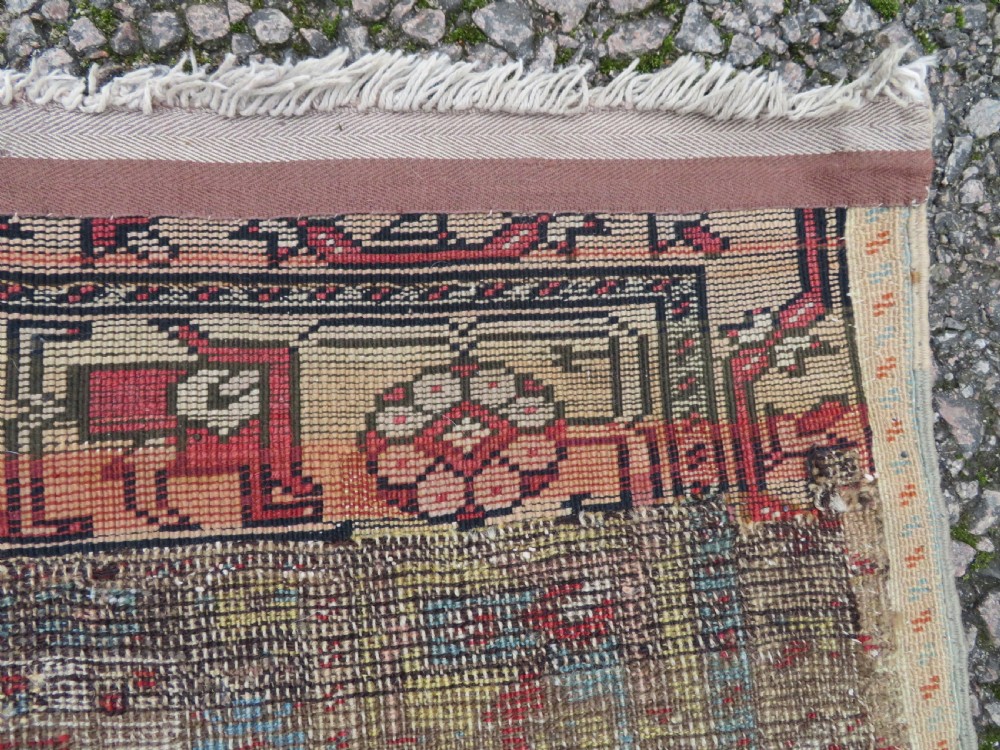 An antique hand-knotted Turkish Ladik wool prayer rug featuring a central pale blue mihrab niche, inverted tulip motifs, and multi-coloured geometric borders. View XX