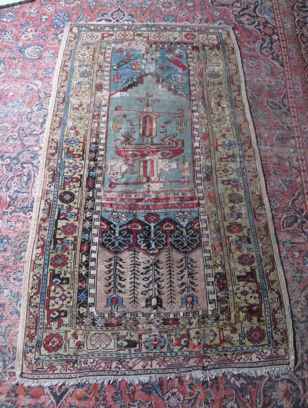 An antique hand-knotted Turkish Ladik wool prayer rug featuring a central pale blue mihrab niche, inverted tulip motifs, and multi-coloured geometric borders. View XXIX