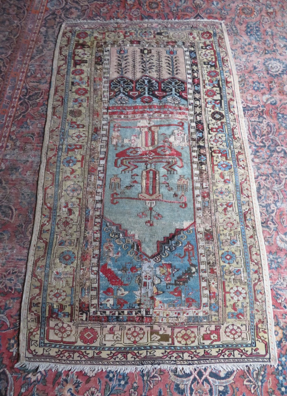 An antique hand-knotted Turkish Ladik wool prayer rug featuring a central pale blue mihrab niche, inverted tulip motifs, and multi-coloured geometric borders. View XXX