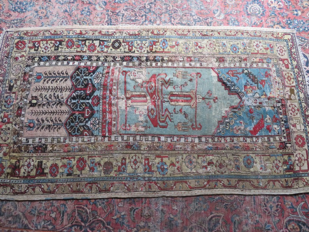 An antique hand-knotted Turkish Ladik wool prayer rug featuring a central pale blue mihrab niche, inverted tulip motifs, and multi-coloured geometric borders. View XXXI