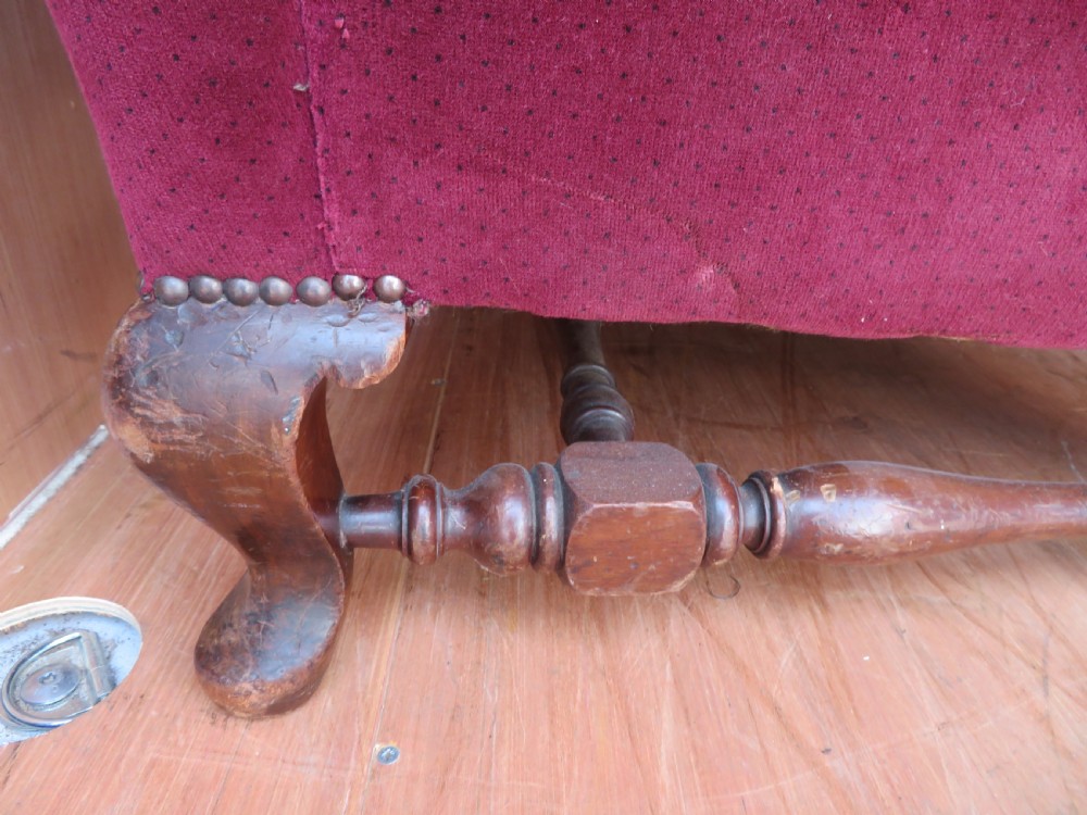 An antique wingback armchair upholstered in crimson velvet with turned wooden stretchers and cabriole front legs. View II