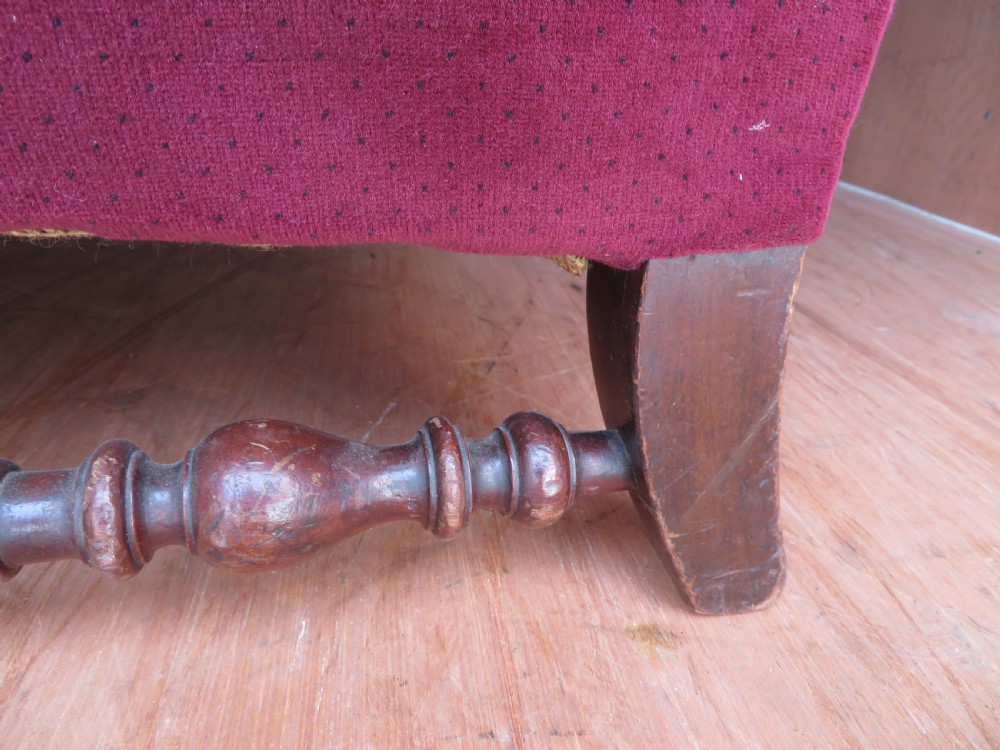 An antique wingback armchair upholstered in crimson velvet with turned wooden stretchers and cabriole front legs. View III