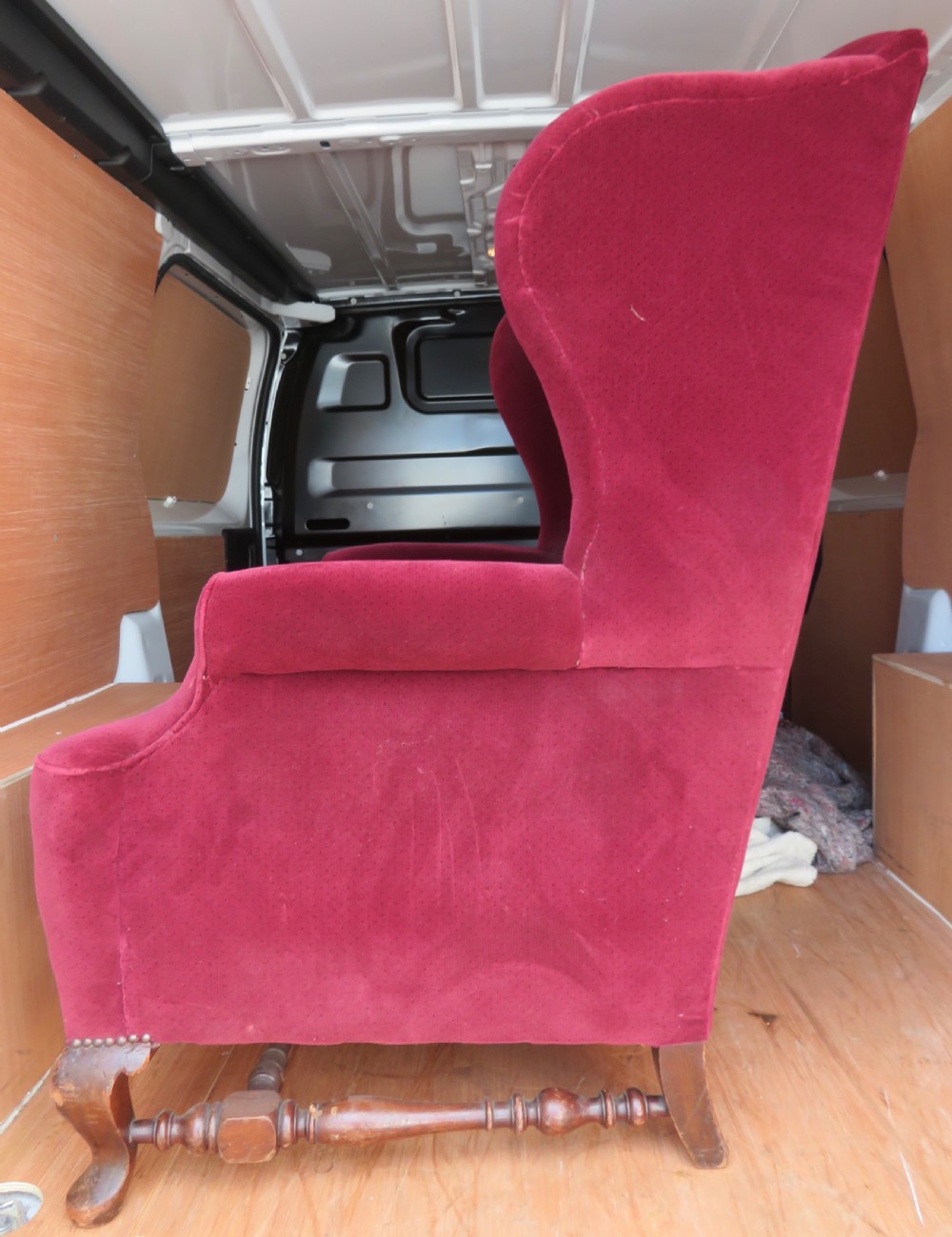 An antique wingback armchair upholstered in crimson velvet with turned wooden stretchers and cabriole front legs. View IV