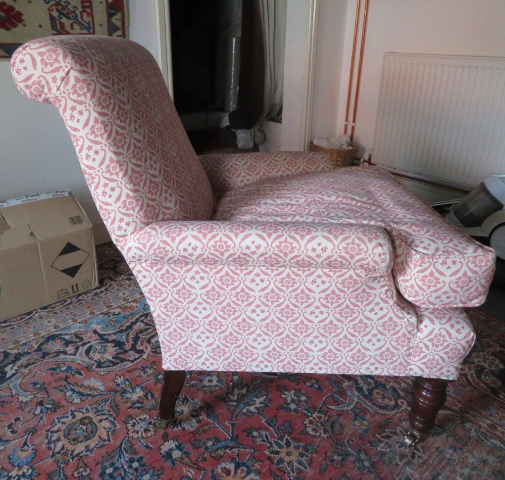 An upholstered Victorian armchair featuring patterned pink and cream fabric, turned dark timber legs, and brass castors. View IV