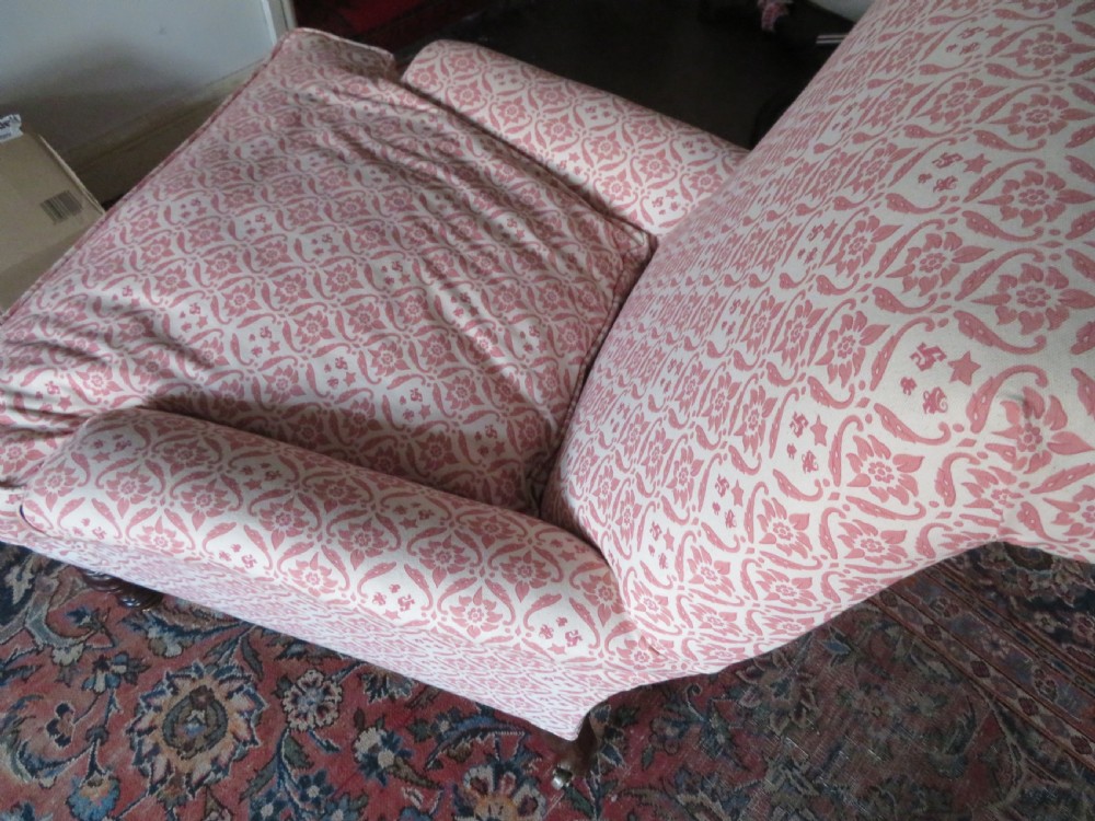 An upholstered Victorian armchair featuring patterned pink and cream fabric, turned dark timber legs, and brass castors. View VII