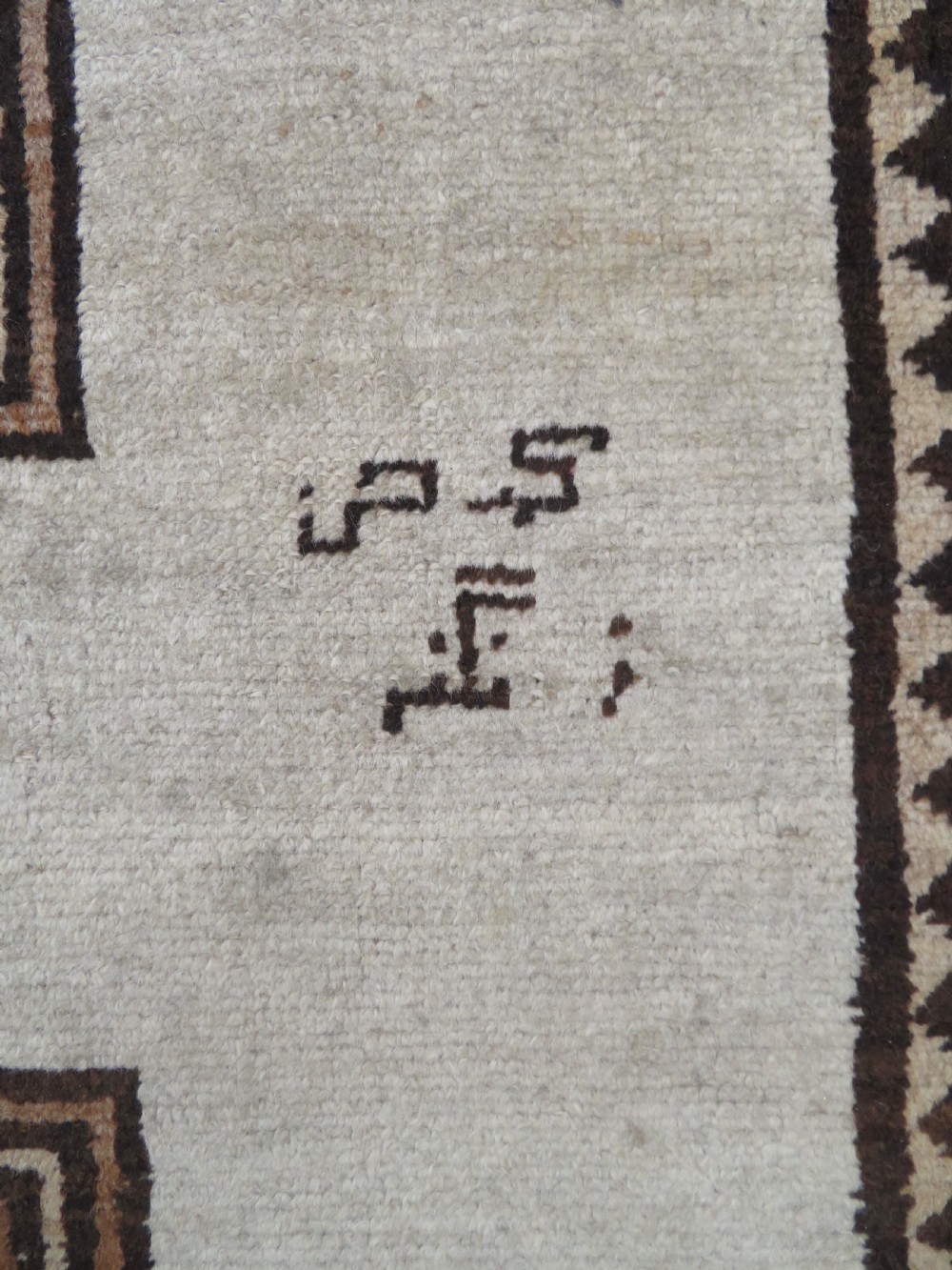 An antique hand-knotted wool Gabbeh rug with five central geometric diamond medallions in brown set against a cream field with a detailed geometric border. View V