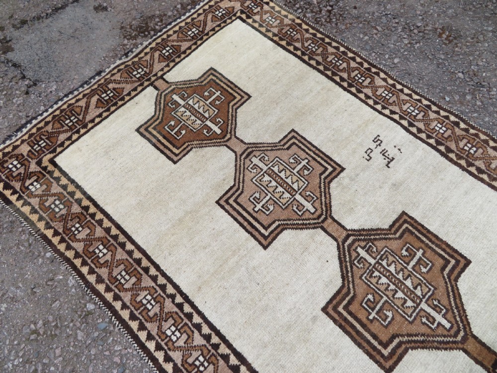 An antique hand-knotted wool Gabbeh rug with five central geometric diamond medallions in brown set against a cream field with a detailed geometric border. View VII
