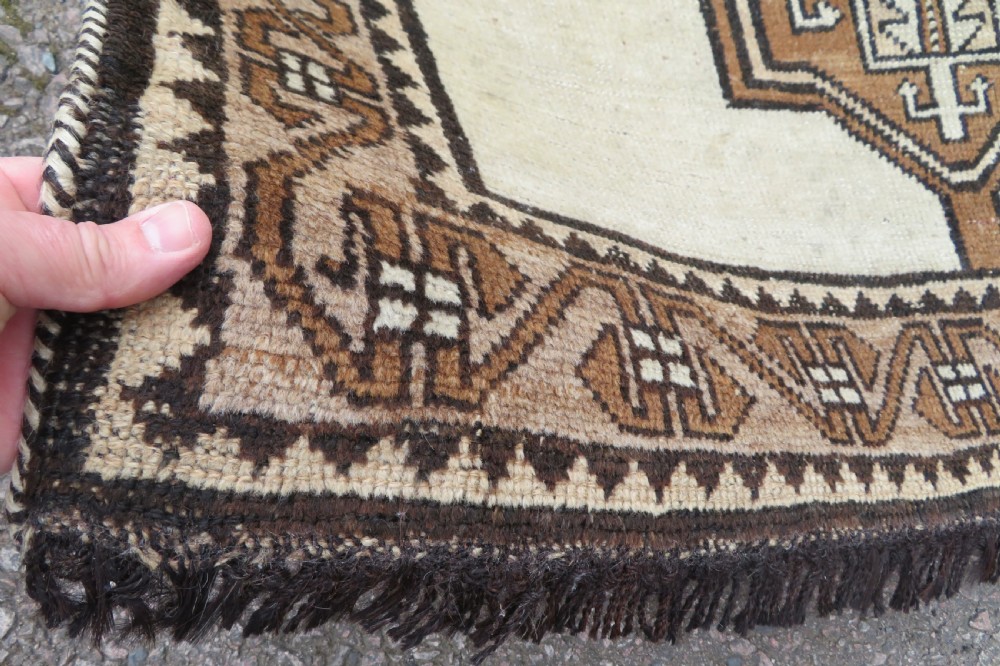 An antique hand-knotted wool Gabbeh rug with five central geometric diamond medallions in brown set against a cream field with a detailed geometric border. View IX