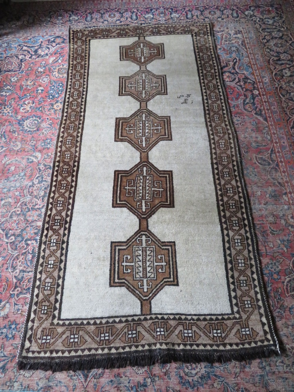 An antique hand-knotted wool Gabbeh rug with five central geometric diamond medallions in brown set against a cream field with a detailed geometric border. View XVII