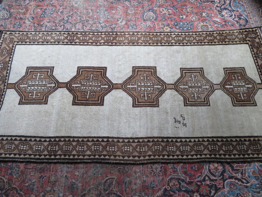 An antique hand-knotted wool Gabbeh rug with five central geometric diamond medallions in brown set against a cream field with a detailed geometric border. View XVIII