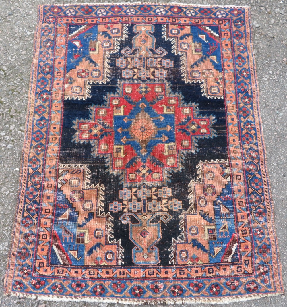 An antique hand-knotted Afshar wool rug featuring a central stepped geometric medallion in rust red and blue framed by intricate tribal borders.