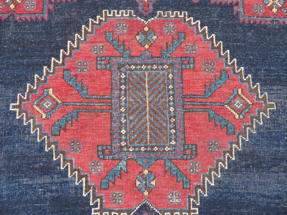 A hand-knotted antique Afshar tribal wool rug featuring a red stepped medallion on an indigo blue field surrounded by geometric borders. View III