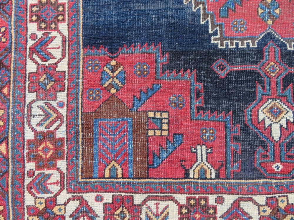 A hand-knotted antique Afshar tribal wool rug featuring a red stepped medallion on an indigo blue field surrounded by geometric borders. View IV