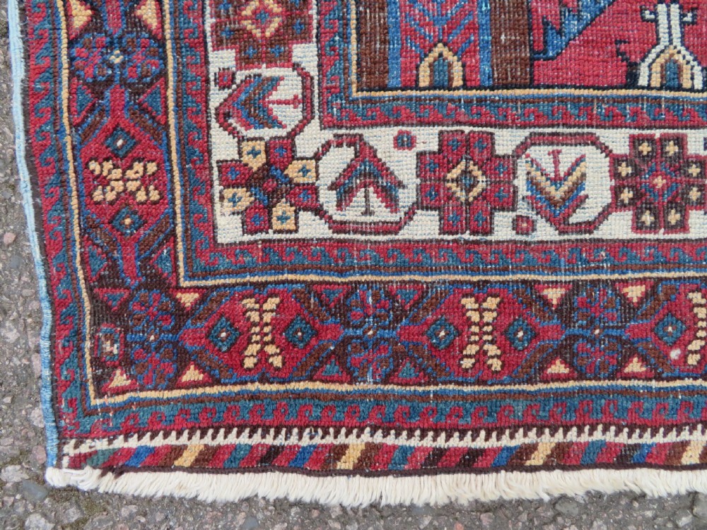 A hand-knotted antique Afshar tribal wool rug featuring a red stepped medallion on an indigo blue field surrounded by geometric borders. View VI