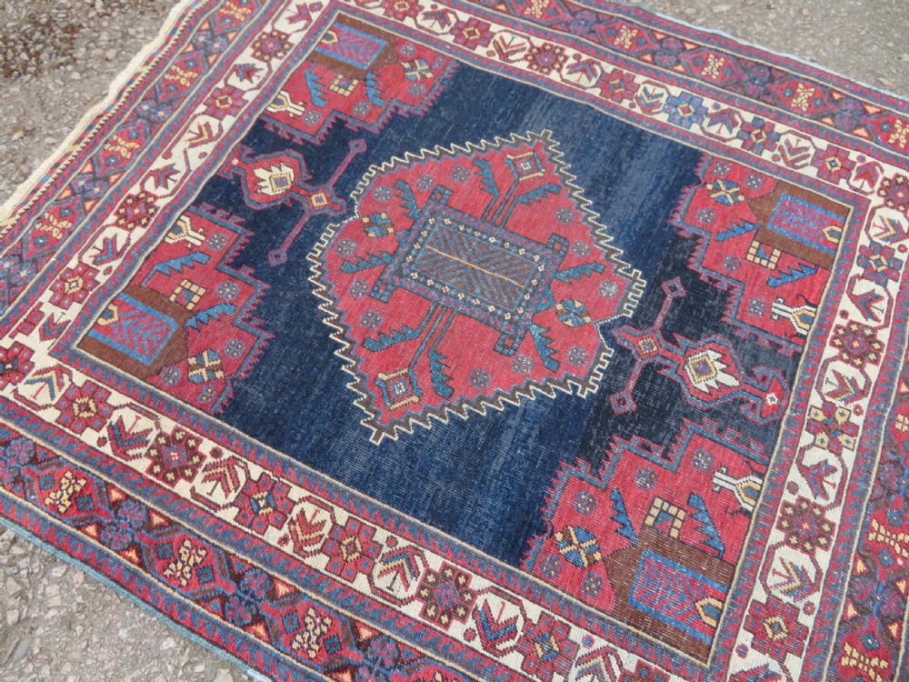 A hand-knotted antique Afshar tribal wool rug featuring a red stepped medallion on an indigo blue field surrounded by geometric borders. View VIII
