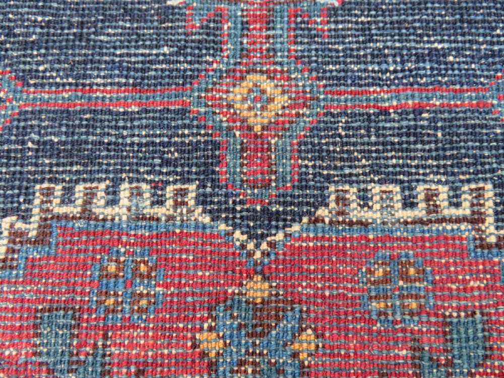A hand-knotted antique Afshar tribal wool rug featuring a red stepped medallion on an indigo blue field surrounded by geometric borders. View XI