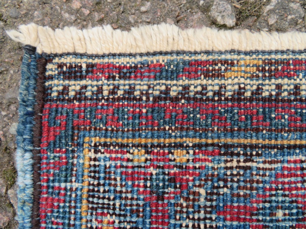 A hand-knotted antique Afshar tribal wool rug featuring a red stepped medallion on an indigo blue field surrounded by geometric borders. View XII