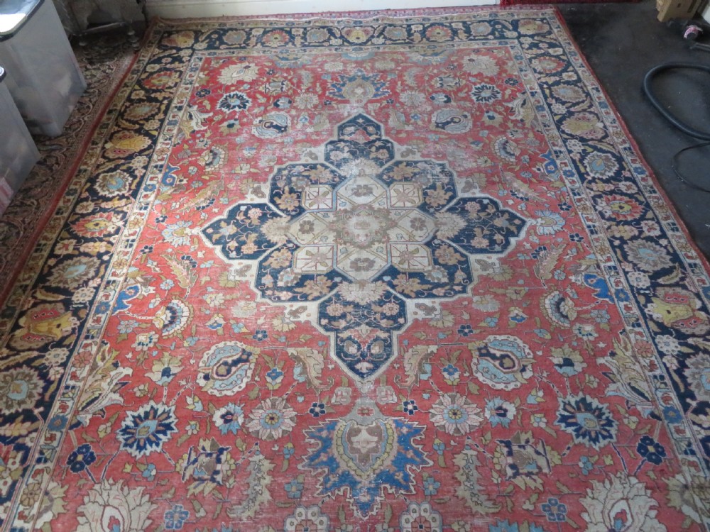 An antique hand-knotted Tabriz wool carpet featuring a central navy and cream medallion on a terracotta field with intricate floral borders. View V