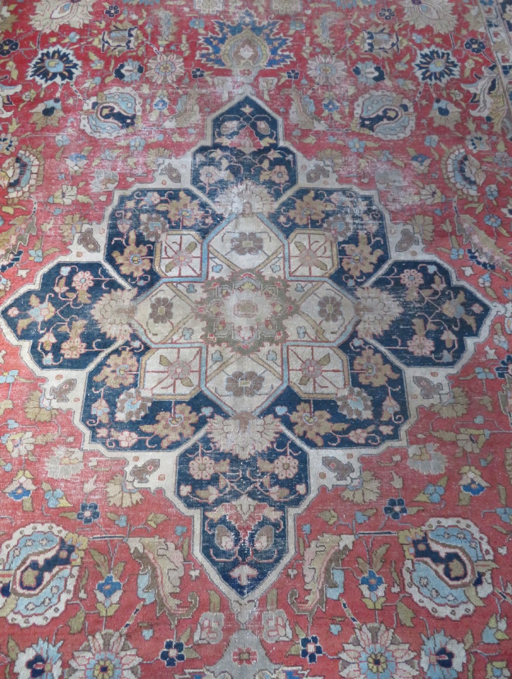 An antique hand-knotted Tabriz wool carpet featuring a central navy and cream medallion on a terracotta field with intricate floral borders. View VI
