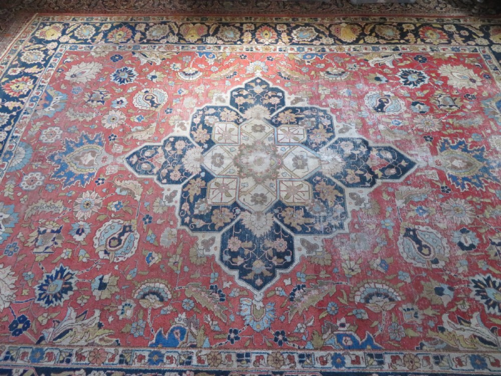 An antique hand-knotted Tabriz wool carpet featuring a central navy and cream medallion on a terracotta field with intricate floral borders. View XII