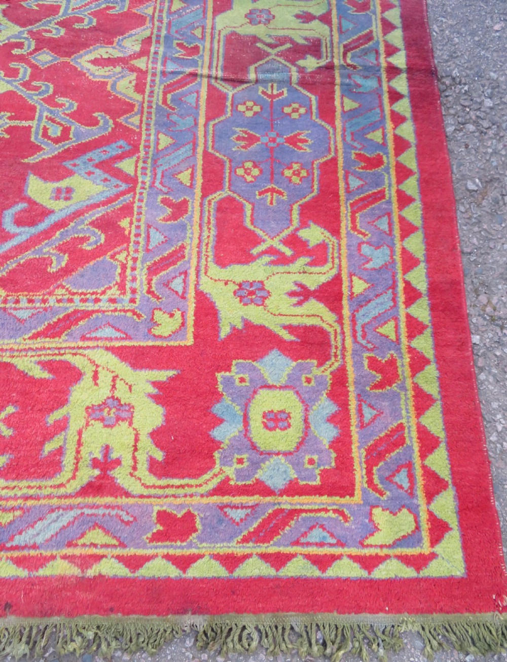 A large antique wool Ushak carpet featuring a coral red field decorated with light green and pastel medallion motifs and a patterned border. View XI