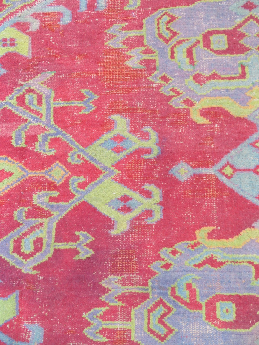 A large antique wool Ushak carpet featuring a coral red field decorated with light green and pastel medallion motifs and a patterned border. View XVII