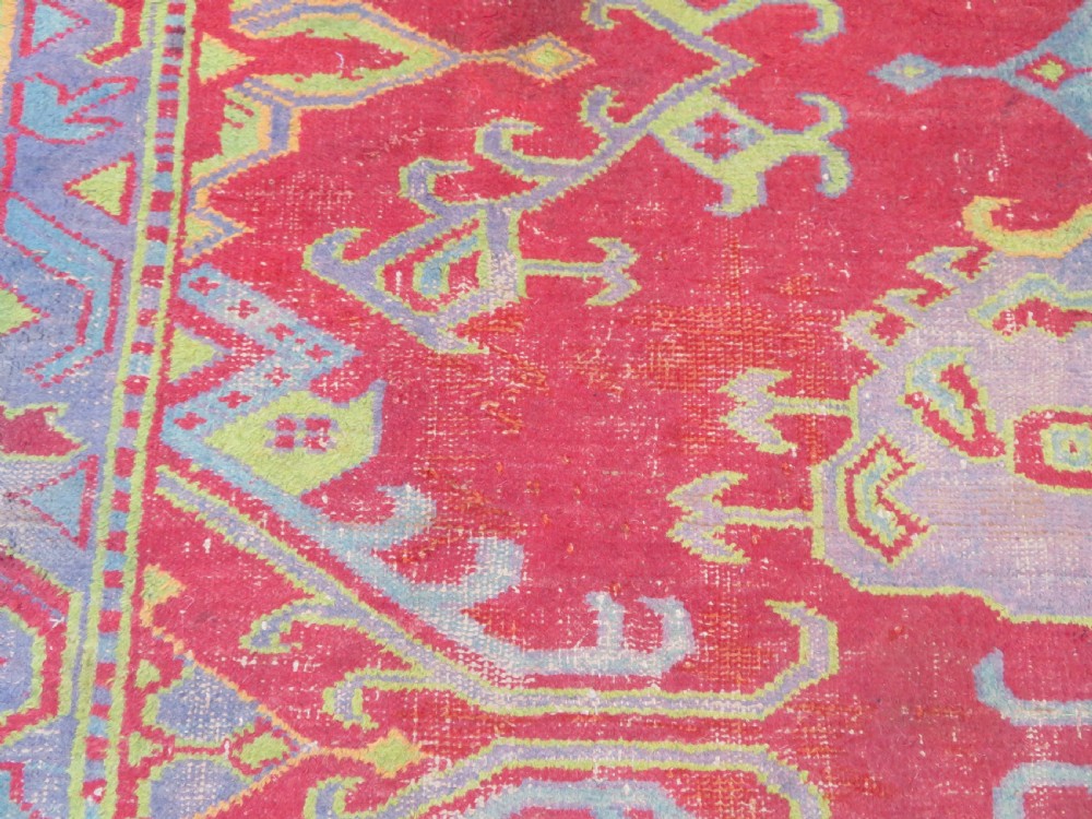 A large antique wool Ushak carpet featuring a coral red field decorated with light green and pastel medallion motifs and a patterned border. View XVIII