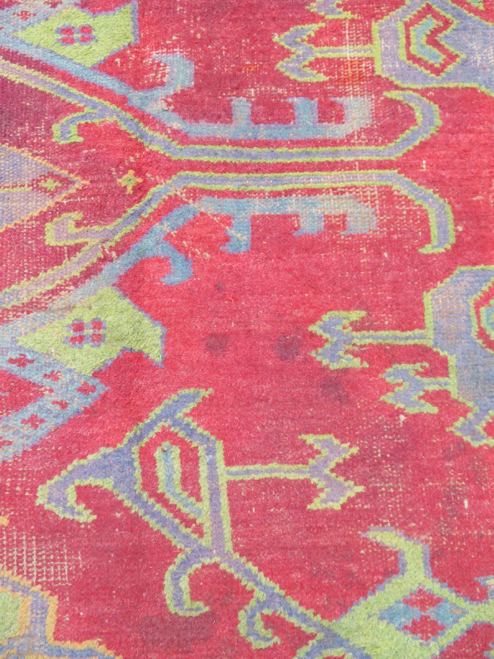 A large antique wool Ushak carpet featuring a coral red field decorated with light green and pastel medallion motifs and a patterned border. View XX
