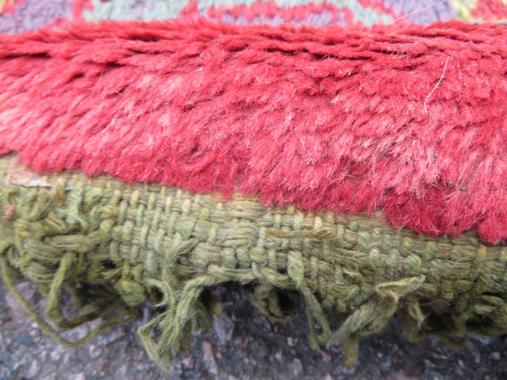 A large antique wool Ushak carpet featuring a coral red field decorated with light green and pastel medallion motifs and a patterned border. View XXIV