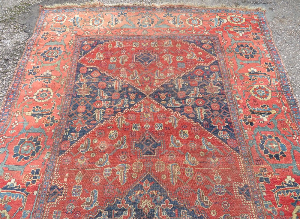 An antique Kurdish Bidjar Kelleh hand-knotted carpet featuring geometric diamond medallions on a terracotta red field with dark navy blue borders. View VI