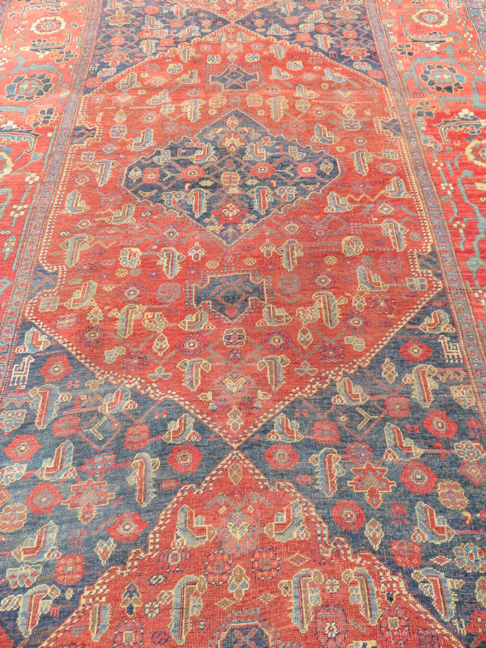 An antique Kurdish Bidjar Kelleh hand-knotted carpet featuring geometric diamond medallions on a terracotta red field with dark navy blue borders. View VII