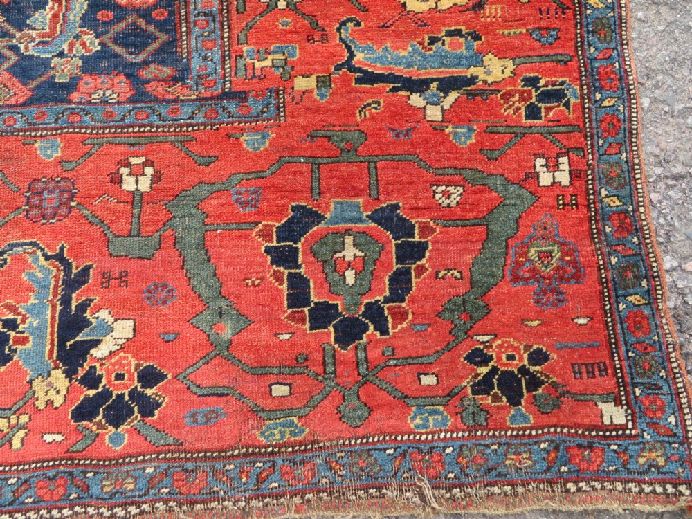 An antique Kurdish Bidjar Kelleh hand-knotted carpet featuring geometric diamond medallions on a terracotta red field with dark navy blue borders. View X