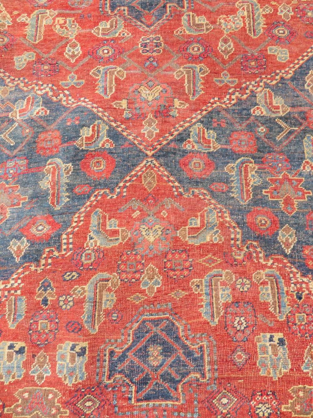 An antique Kurdish Bidjar Kelleh hand-knotted carpet featuring geometric diamond medallions on a terracotta red field with dark navy blue borders. View XII
