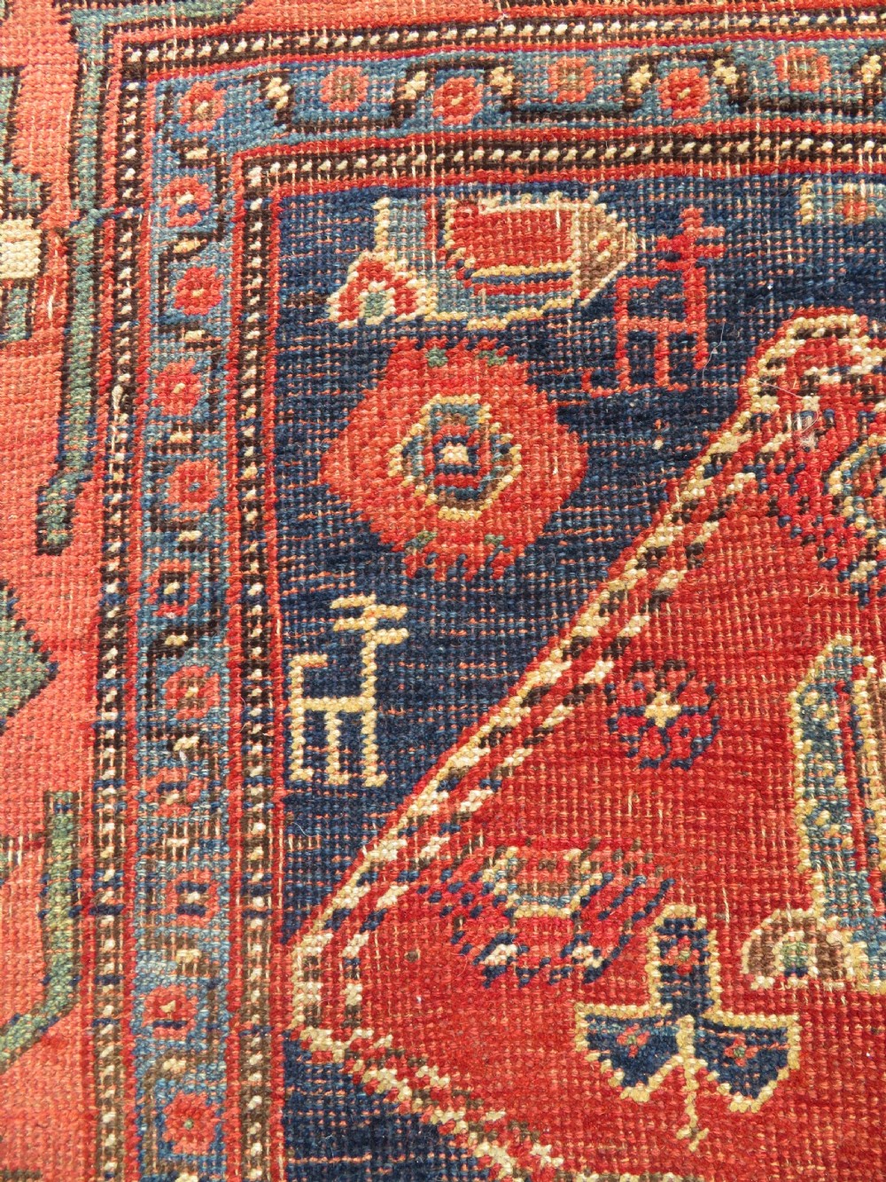 An antique Kurdish Bidjar Kelleh hand-knotted carpet featuring geometric diamond medallions on a terracotta red field with dark navy blue borders. View XVII
