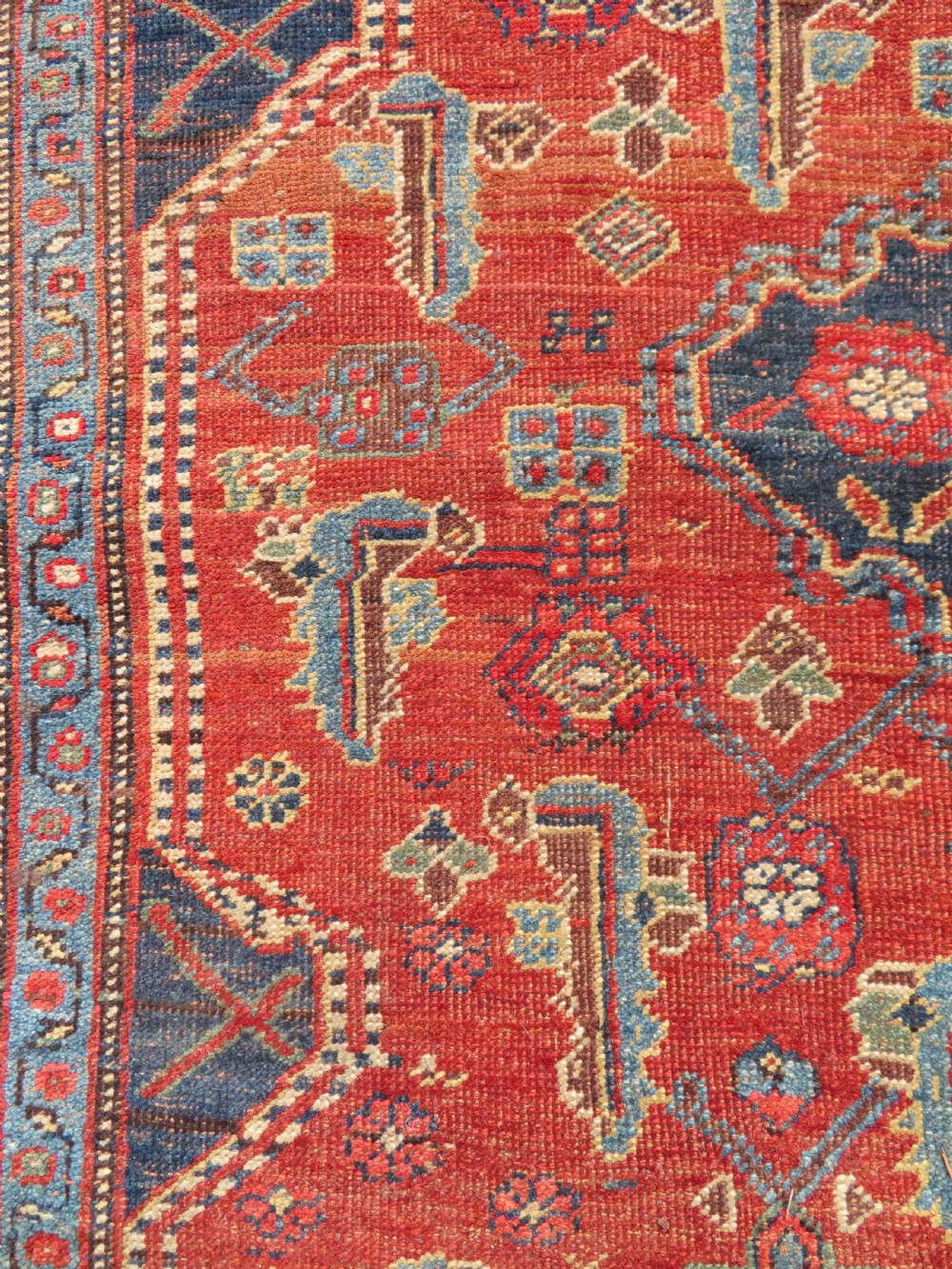An antique Kurdish Bidjar Kelleh hand-knotted carpet featuring geometric diamond medallions on a terracotta red field with dark navy blue borders. View XXV