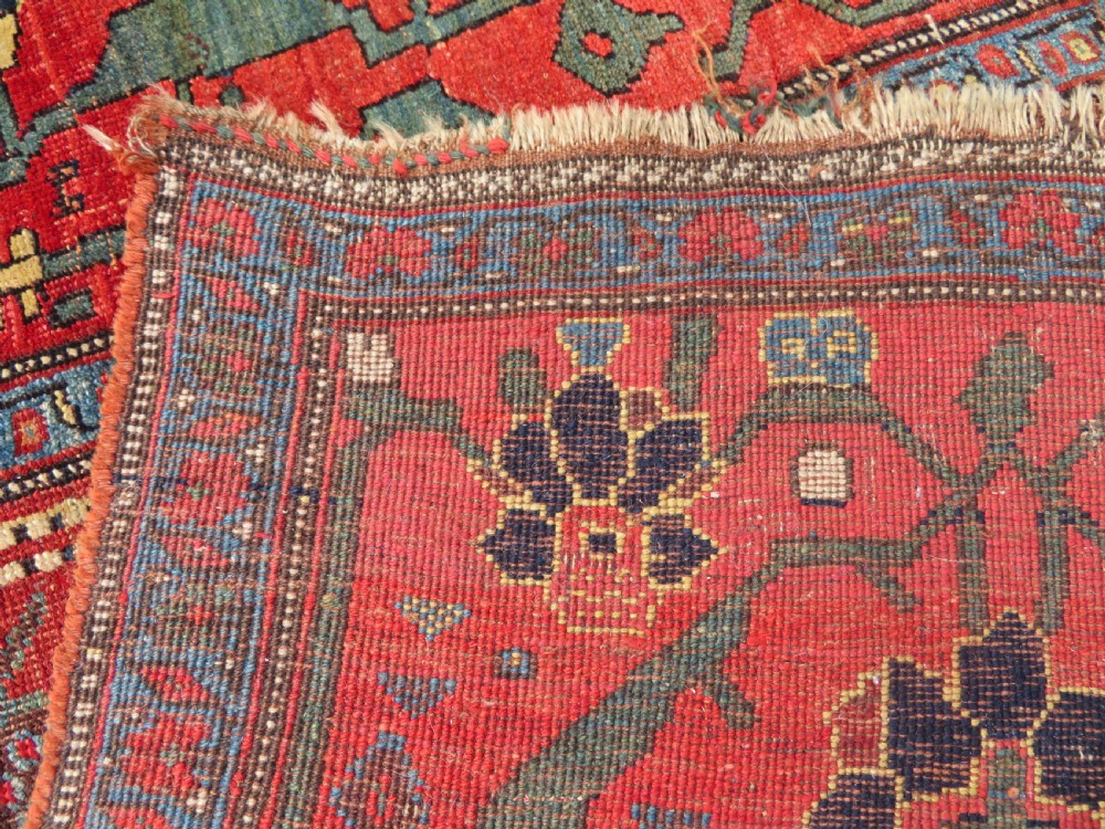 An antique Kurdish Bidjar Kelleh hand-knotted carpet featuring geometric diamond medallions on a terracotta red field with dark navy blue borders. View XXX