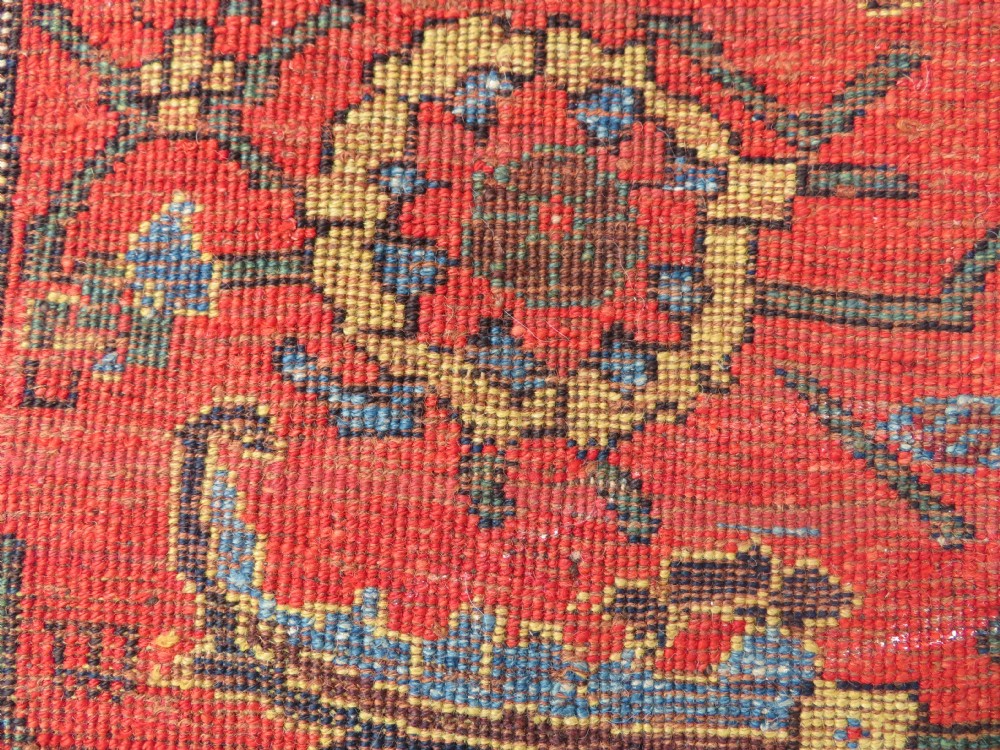An antique Kurdish Bidjar Kelleh hand-knotted carpet featuring geometric diamond medallions on a terracotta red field with dark navy blue borders. View XXXI