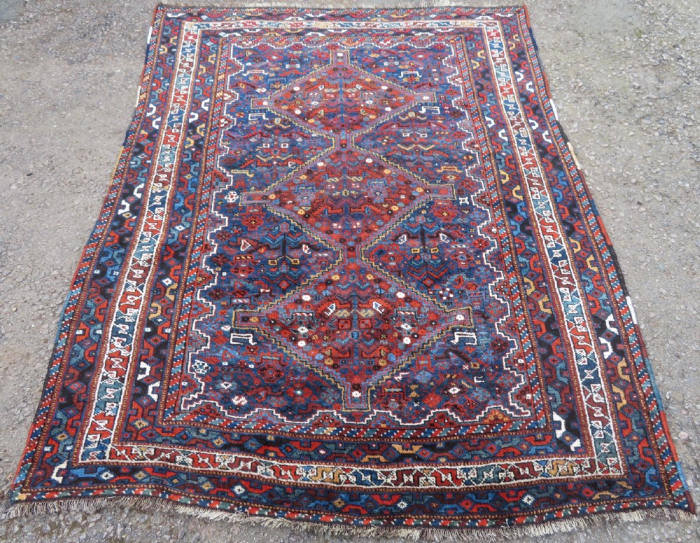An antique Khamseh hand-knotted wool tribal rug featuring three central diamond medallions surrounded by small bird and geometric motifs in deep blue, terracotta red, and cream. View II