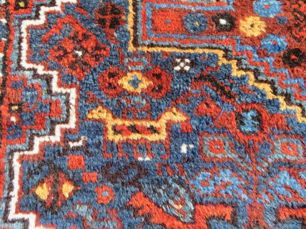 An antique Khamseh hand-knotted wool tribal rug featuring three central diamond medallions surrounded by small bird and geometric motifs in deep blue, terracotta red, and cream. View VII