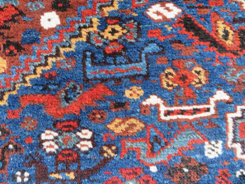 An antique Khamseh hand-knotted wool tribal rug featuring three central diamond medallions surrounded by small bird and geometric motifs in deep blue, terracotta red, and cream. View VIII