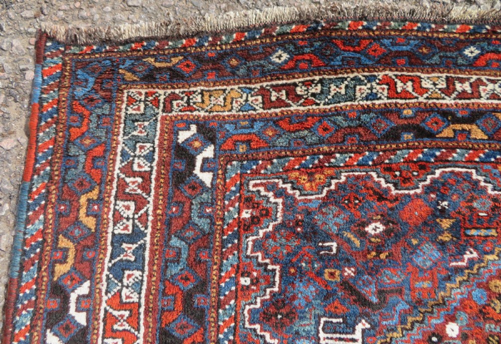 An antique Khamseh hand-knotted wool tribal rug featuring three central diamond medallions surrounded by small bird and geometric motifs in deep blue, terracotta red, and cream. View XIII