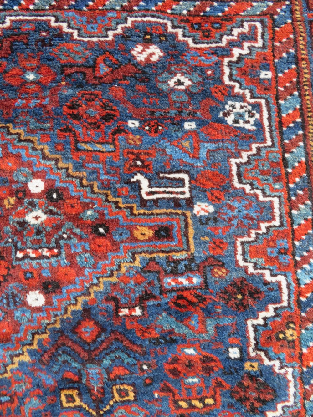 An antique Khamseh hand-knotted wool tribal rug featuring three central diamond medallions surrounded by small bird and geometric motifs in deep blue, terracotta red, and cream. View XIV