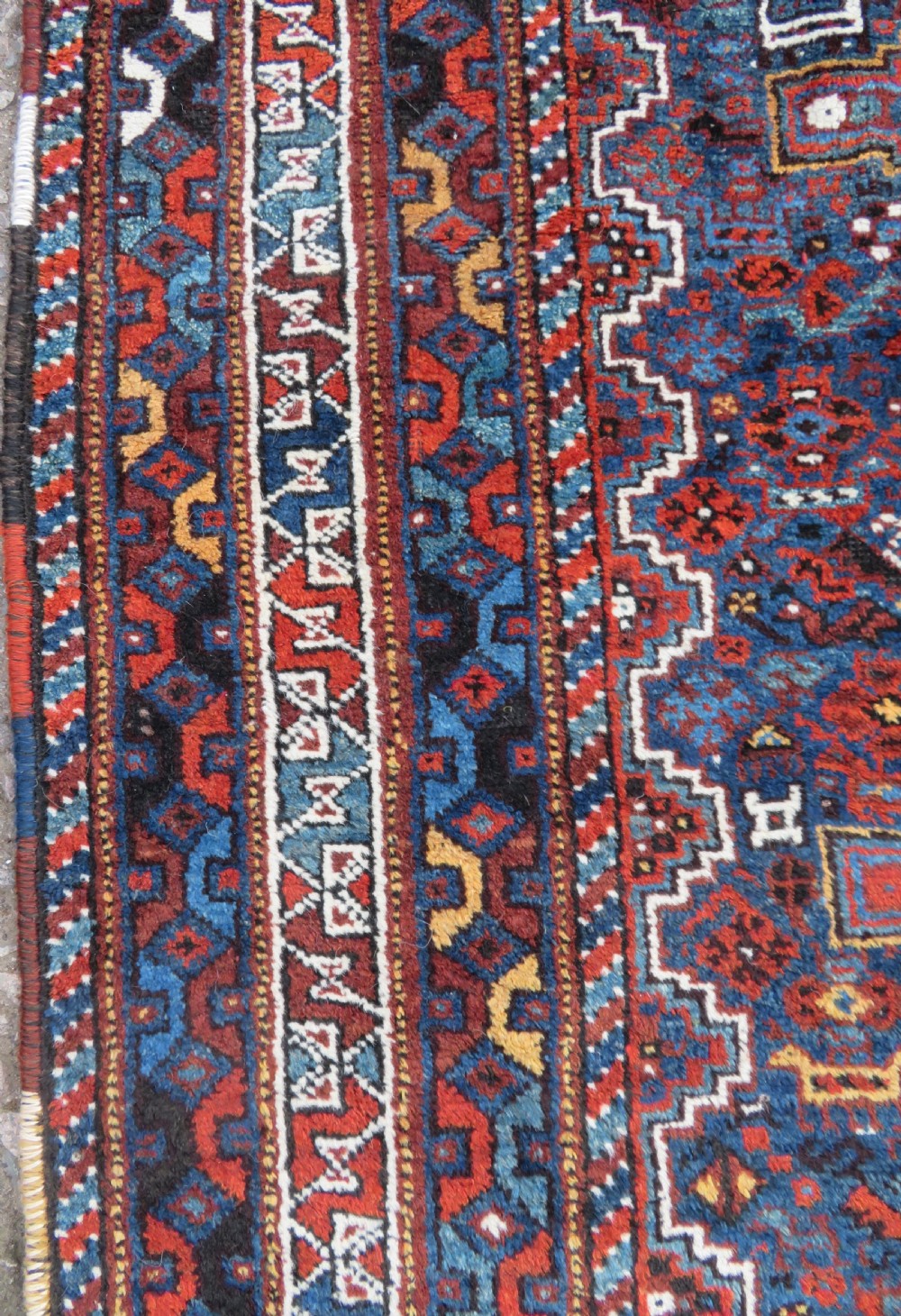 An antique Khamseh hand-knotted wool tribal rug featuring three central diamond medallions surrounded by small bird and geometric motifs in deep blue, terracotta red, and cream. View XVI